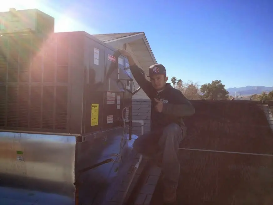 HVAC technician performing HVAC Inspection on a rooftop unit in Hingham