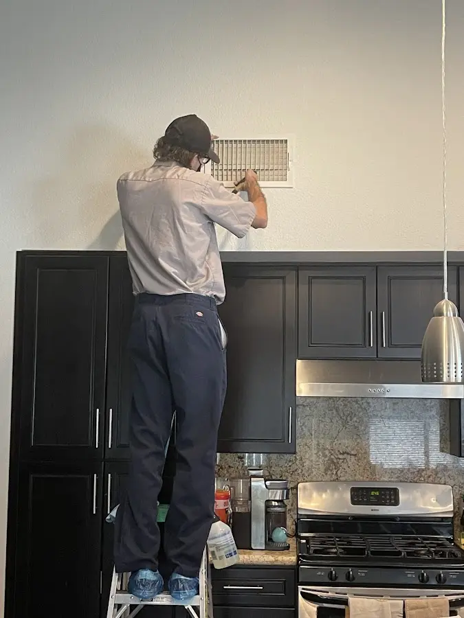 Technician inspecting an air vent during HVAC service in Hingham